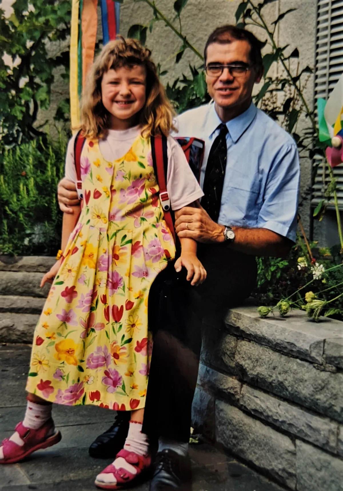 Man sieht ein Mädchen mit seinem Vater am ersten Schultag.